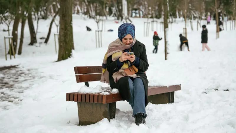 Person sitting alone on a bench looking at their phone