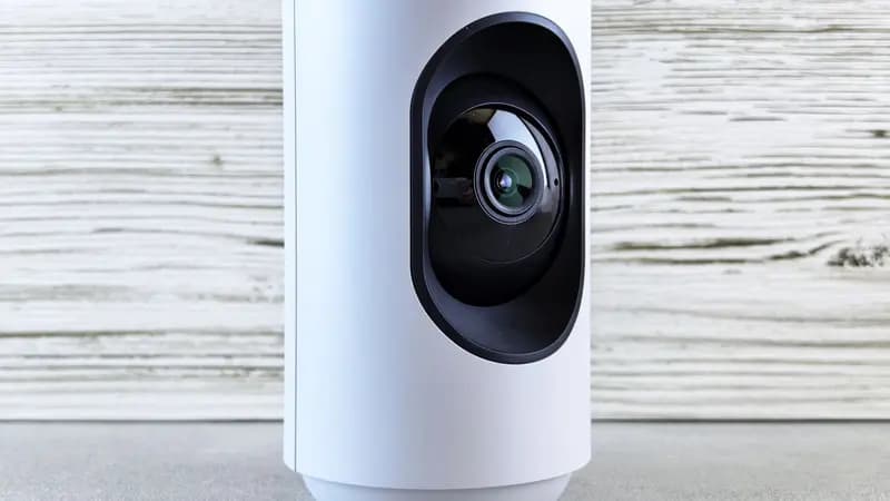 A white indoor smart security camera on a wooden surface