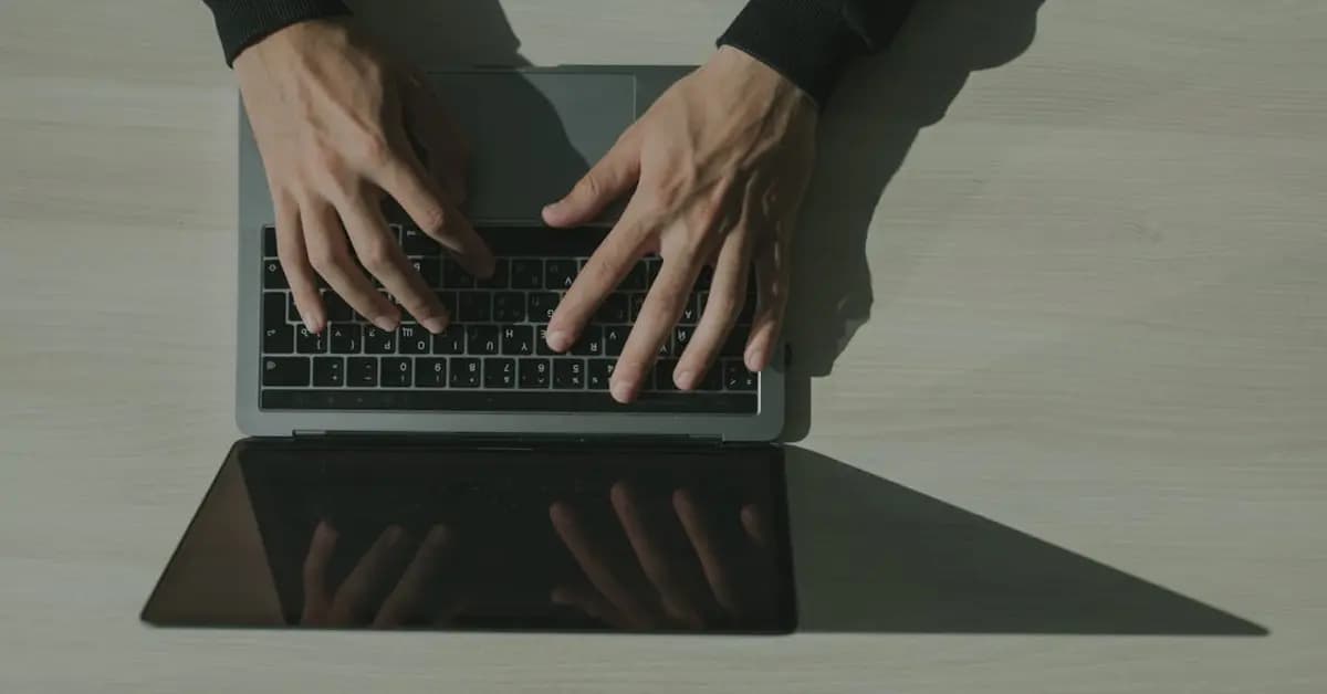 Close-up of hands typing on a laptop keyboard