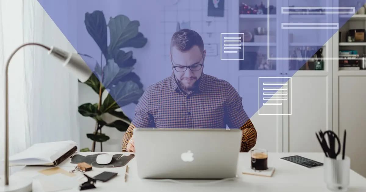 Man in a checked shirt working on a laptop at a home desk