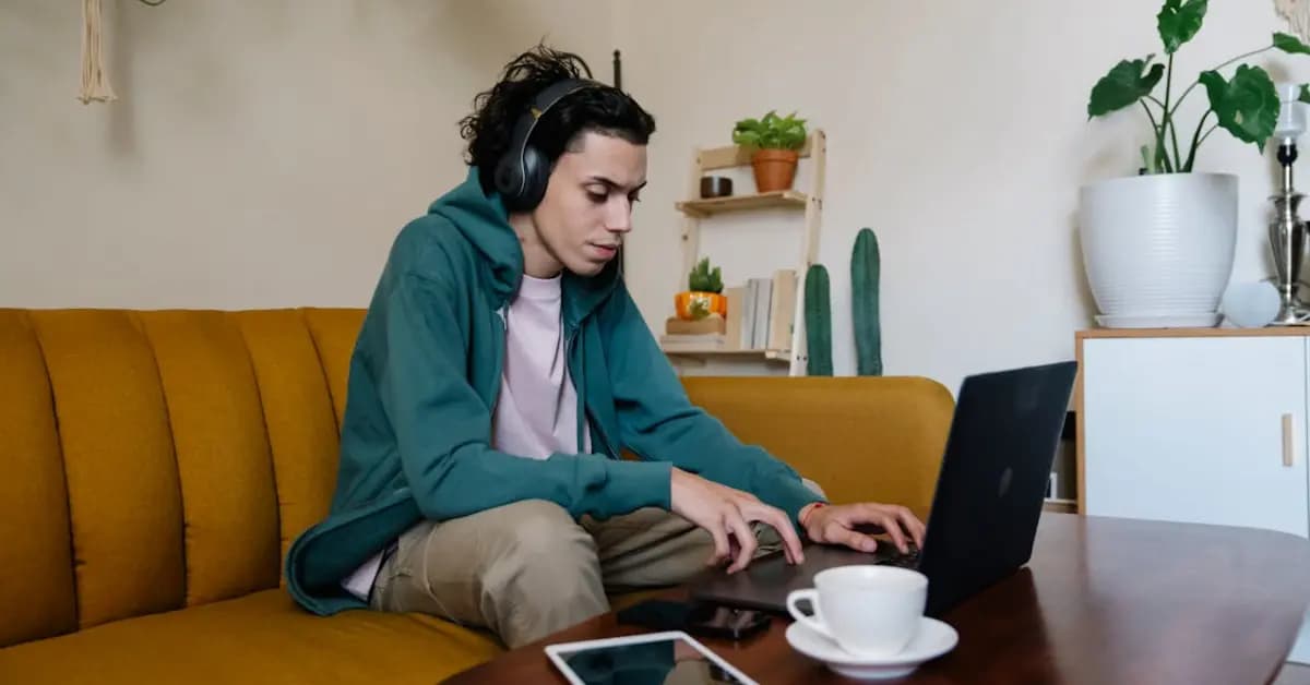 Person focused and typing on a laptop at a home desk with coffee nearby
