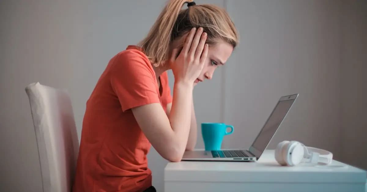 Young woman looking concerned at a laptop screen at home