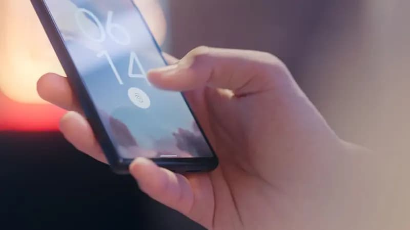 A hand unlocking an Android phone with the fingerprint reader on its screen