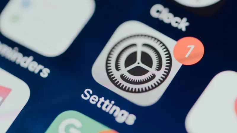 A close-up of the iPhone Settings icon with an update badge showing