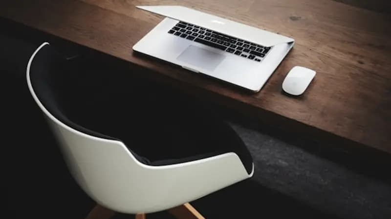 A clean laptop and mouse on a wooden desk