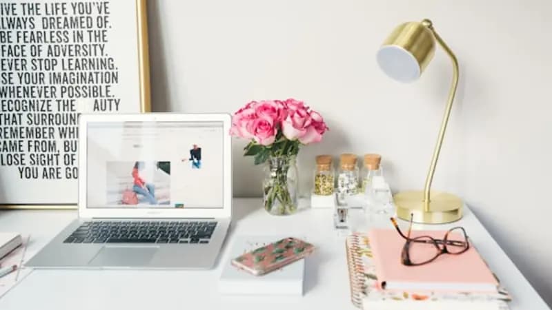 A bright desk with a laptop, lamp and notebook