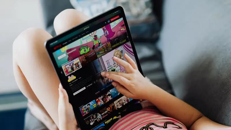 A child's hands holding a tablet showing a kids app