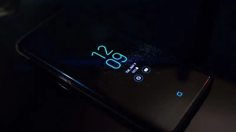 Black Samsung Android smartphone displaying the home screen clock