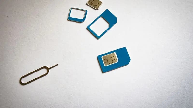 SIM card and ejector tool laid flat on a white surface